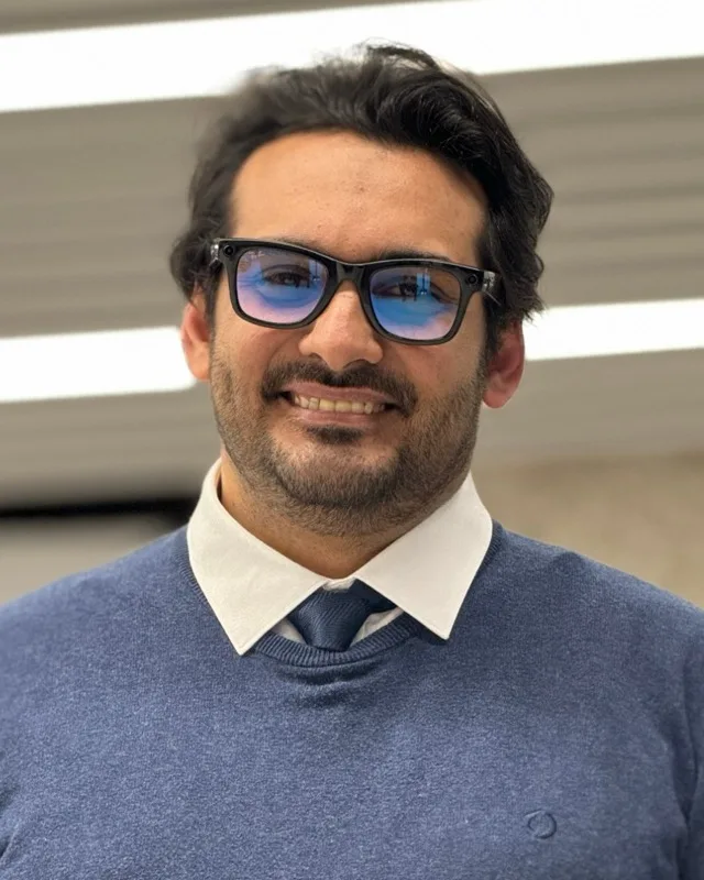 Portrait of Iman Saraei, smiling, in a blue jumper and tie